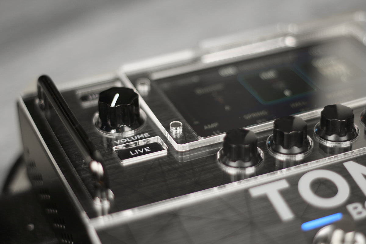 Close-up of the acrylic protector on the IK Multimedia TONEX Board, with cutouts around the volume knob and the Live button